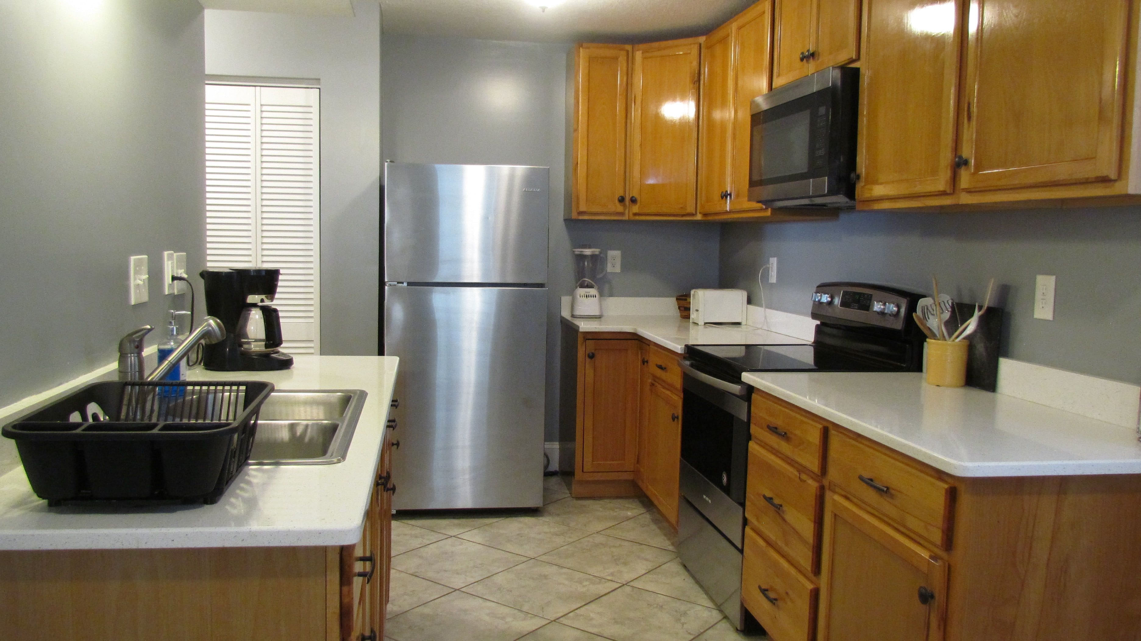 A kitchen with stainless steel appliances, wooden cabinets, a coffee maker, and a toaster.