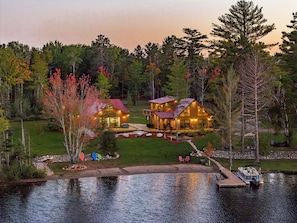 Un chalet au bord du lac, composé de deux bâtiments principaux, d’un quai et d’une pelouse bien entretenue.