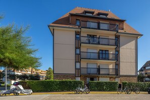 A multi-story residential building with balconies, a parking area, and bicycles. - The Marine Apartment with Terrace & Garden - Welkeys (Villers-sur-Mer)