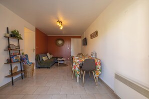 A cozy living room with a sofa, a dining table with chairs, and a television on the wall. - The Marine Apartment with Terrace & Garden - Welkeys (Villers-sur-Mer)