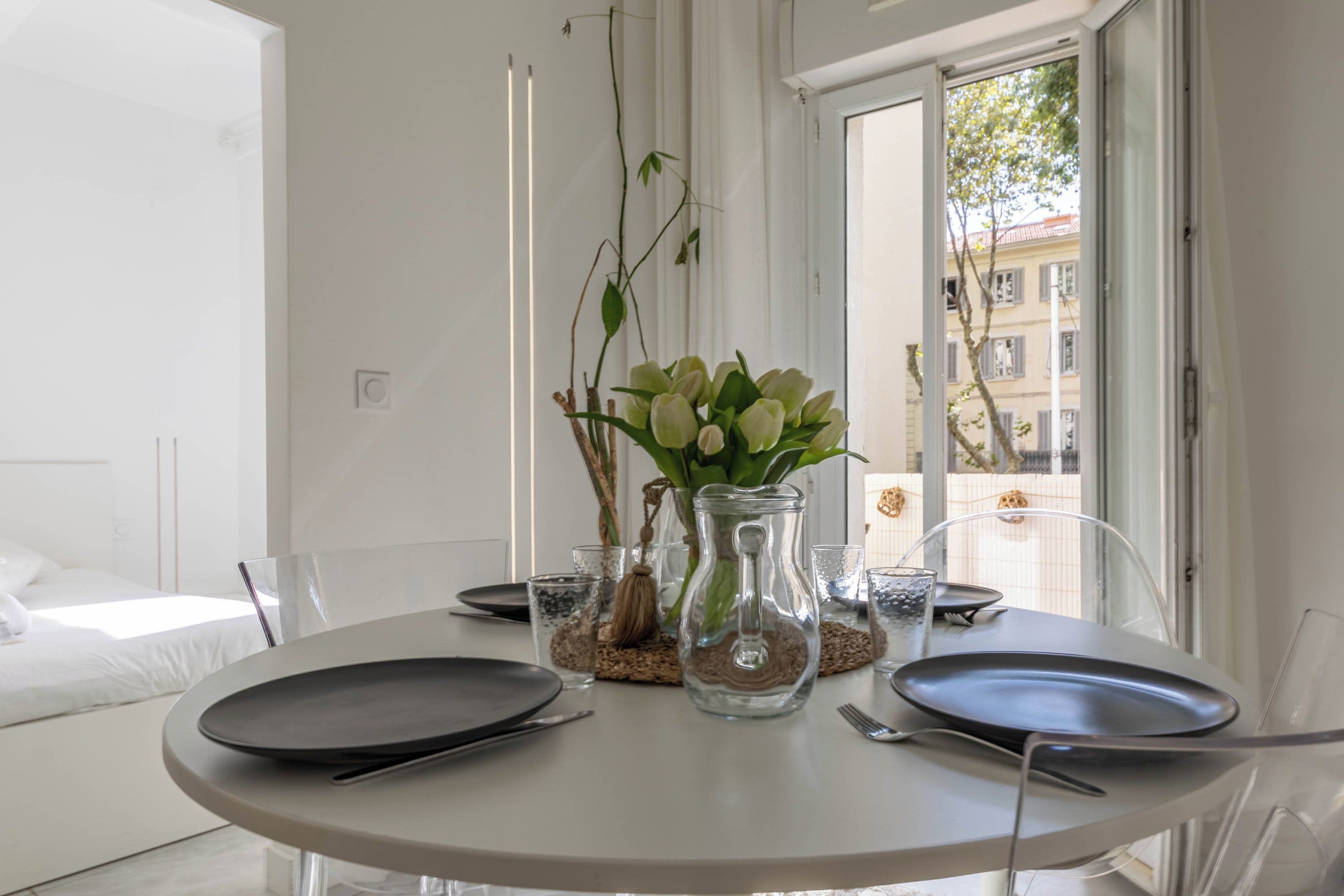 A dining table with plates, cutlery, and a vase with flowers.