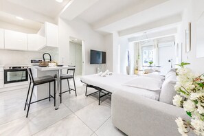 Ein moderner, minimalistischer Wohnraum mit Küche, Essbereich und einer Couch.