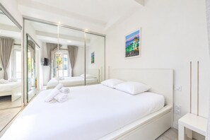 A hotel room with a large bed, a television, a painting, and a sliding glass door leading to an outdoor area. - La Perle du Mourillon 5 minutes from the beach - Welkeys (Toulon)