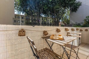 An outdoor seating area with a wooden table and chairs, a woven basket, and a view of buildings and trees. - La Perle du Mourillon 5 minutes from the beach - Welkeys (Toulon)