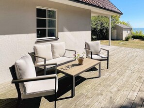 Eine Terrasse im Freien mit einer Couch, Sesseln und einem Tisch.