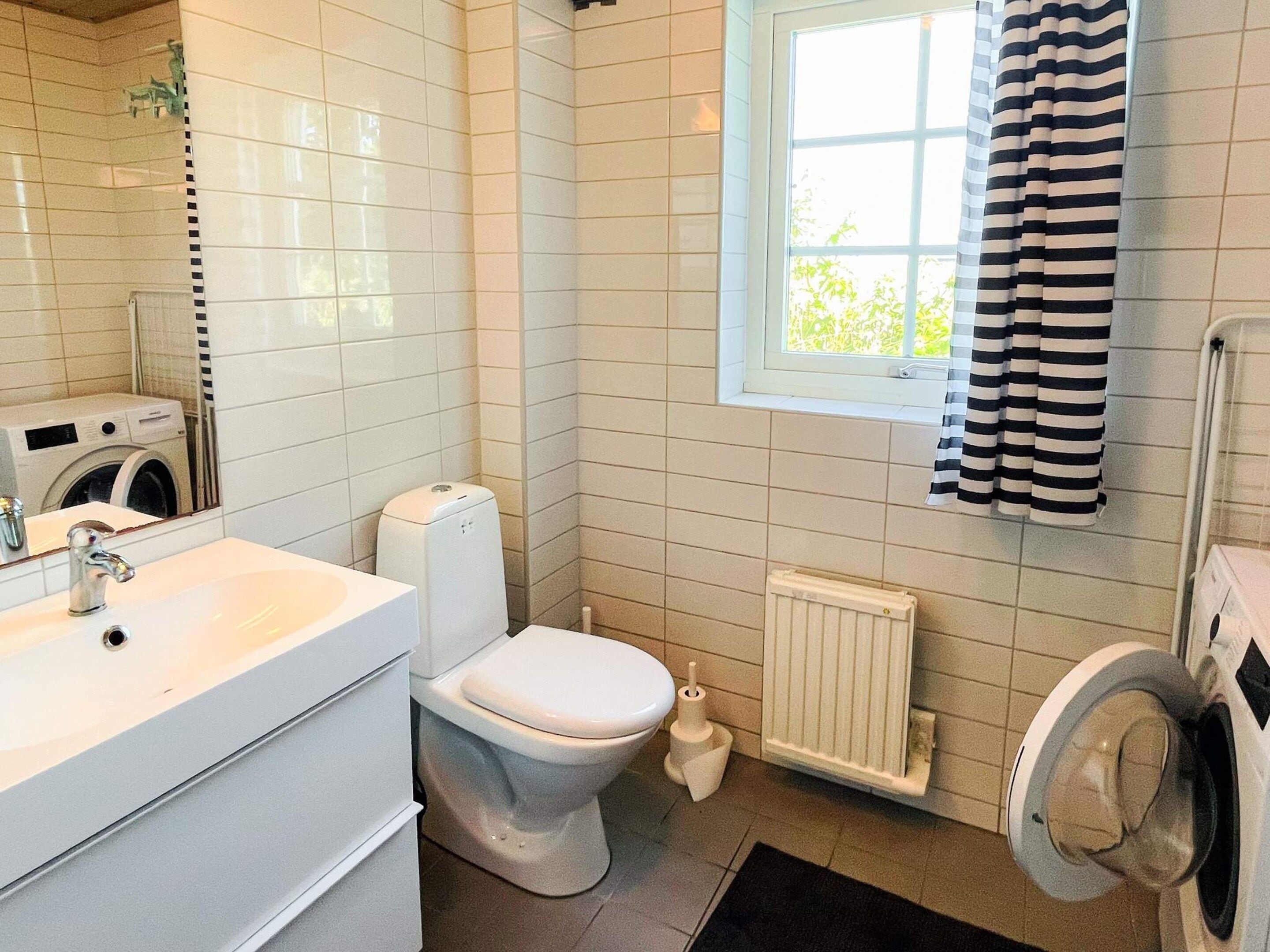 A compact bathroom with a toilet, sink, and washing machine.