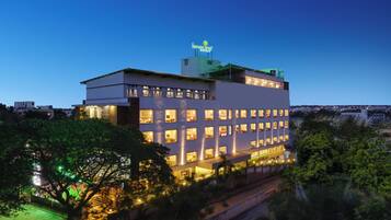 Un hotel de varios pisos con ventanas iluminadas y un letrero en la azotea.