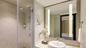 Un baño moderno con cabina de ducha de vidrio, un lavabo con espejo y artículos de aseo en la encimera.