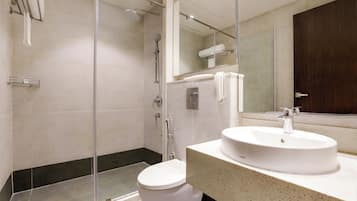 A modern bathroom with a glass-enclosed shower, a white toilet, and a sink with a mirror above it.