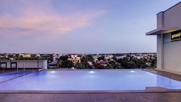 Una piscina infinita en la azotea con vistas a la ciudad, zona de bar y un cartel que indica la zona de piscina.