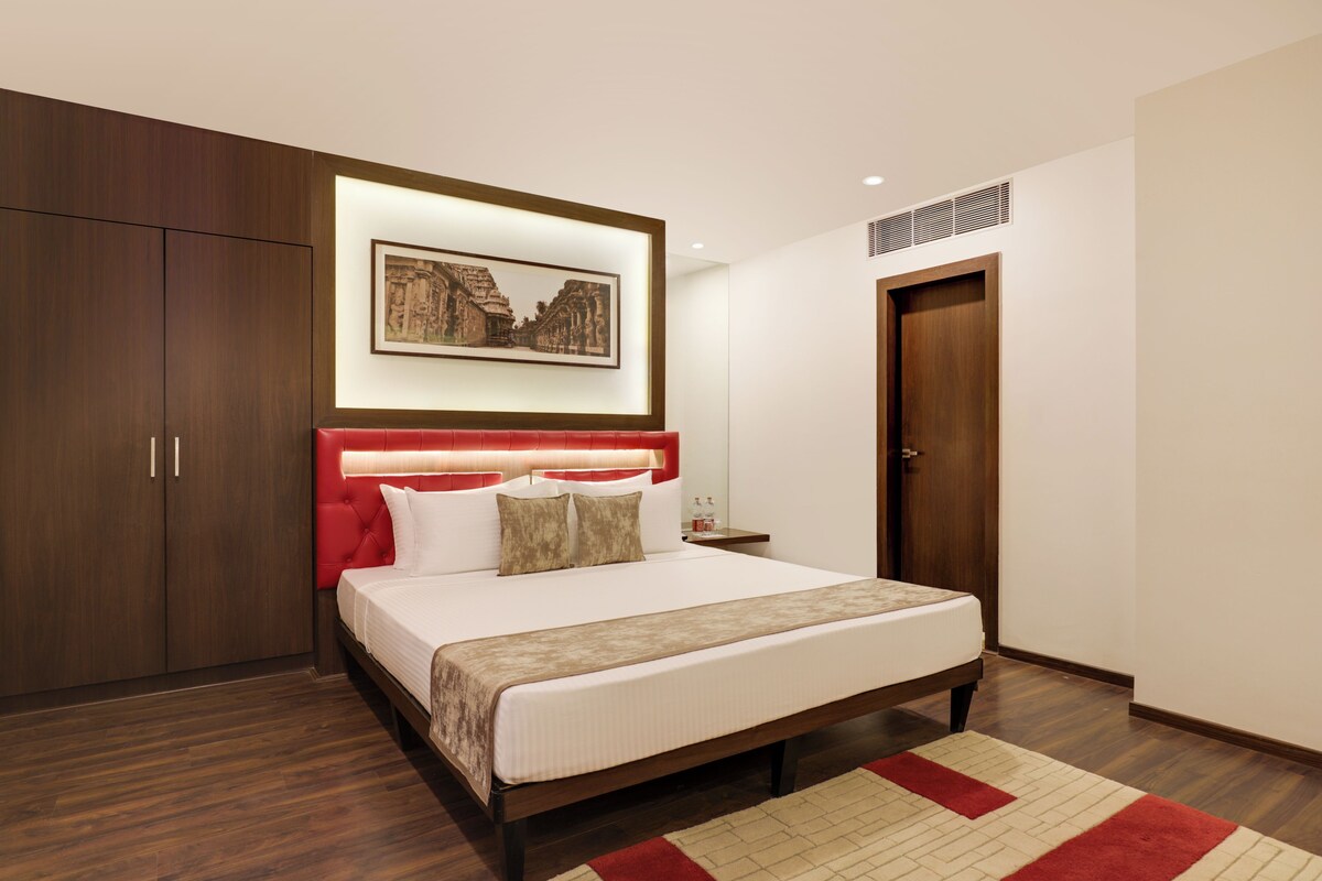 A modern bedroom with a large bed, wooden wardrobe, and a framed picture on the wall.