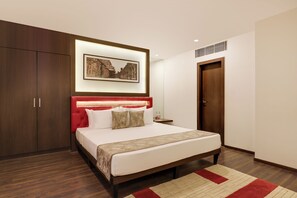 A modern bedroom with a large bed, wooden wardrobe, and a framed picture on the wall. - The Phlox Hotel (Hubballi)