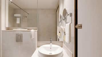 A modern bathroom with a large mirror, a sink, and a towel rack.