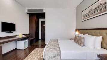 Habitación de hotel con cama, televisor, escritorio y un cuadro en la pared.