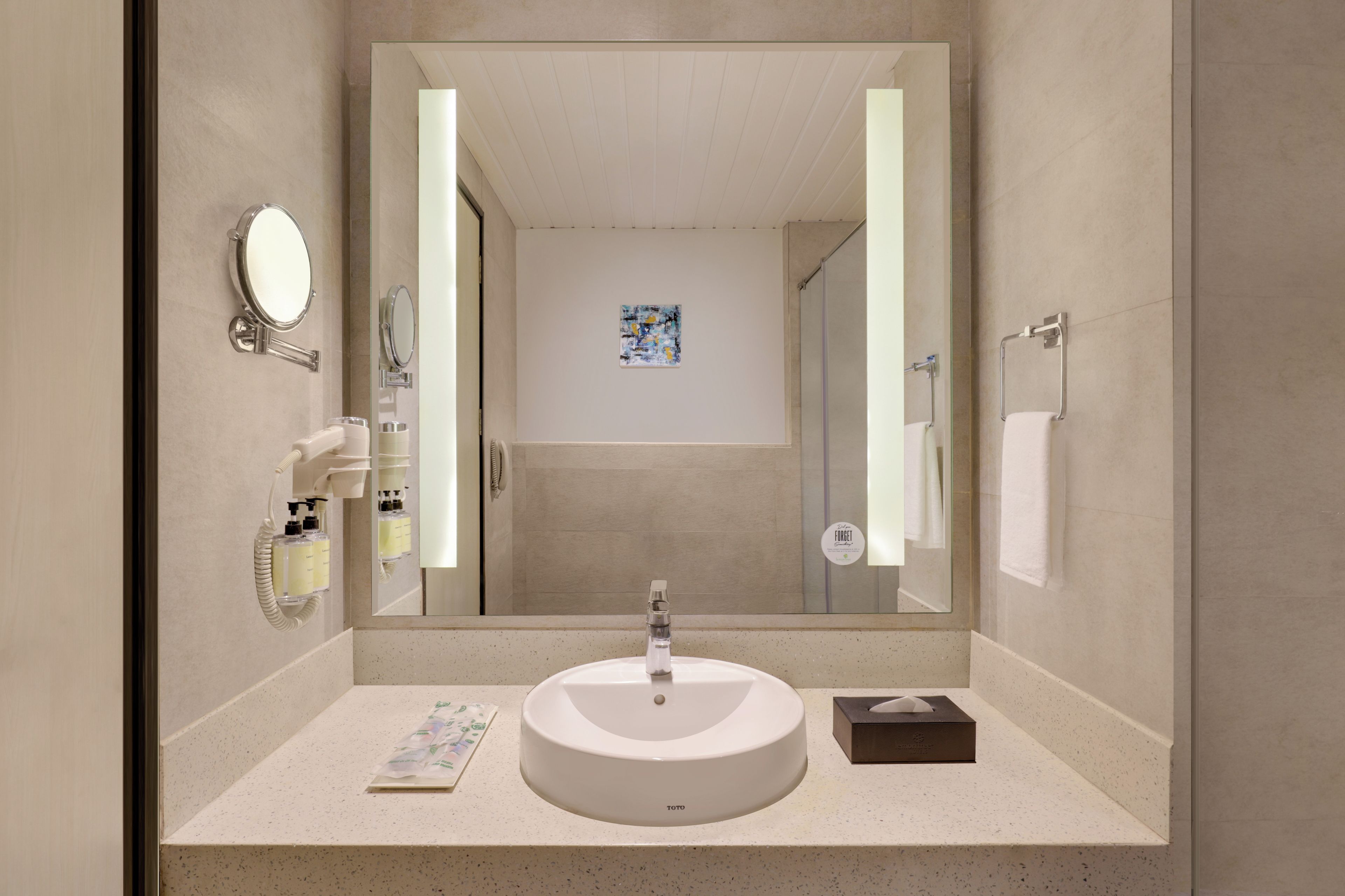 Un baño moderno con un lavabo redondo, un espejo grande y un cabezal de ducha de mano.