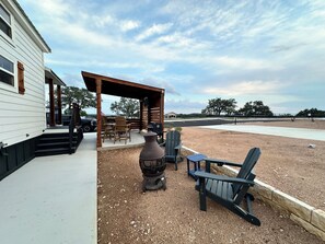 Un patio couvert aménagé avec du mobilier d’extérieur, un barbecue et un grand vase décoratif.