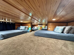 L’intérieur d’une cabane comprend deux lits, un plancher recouvert de moquette, des murs en bois et un plafond avec des poutres apparentes.