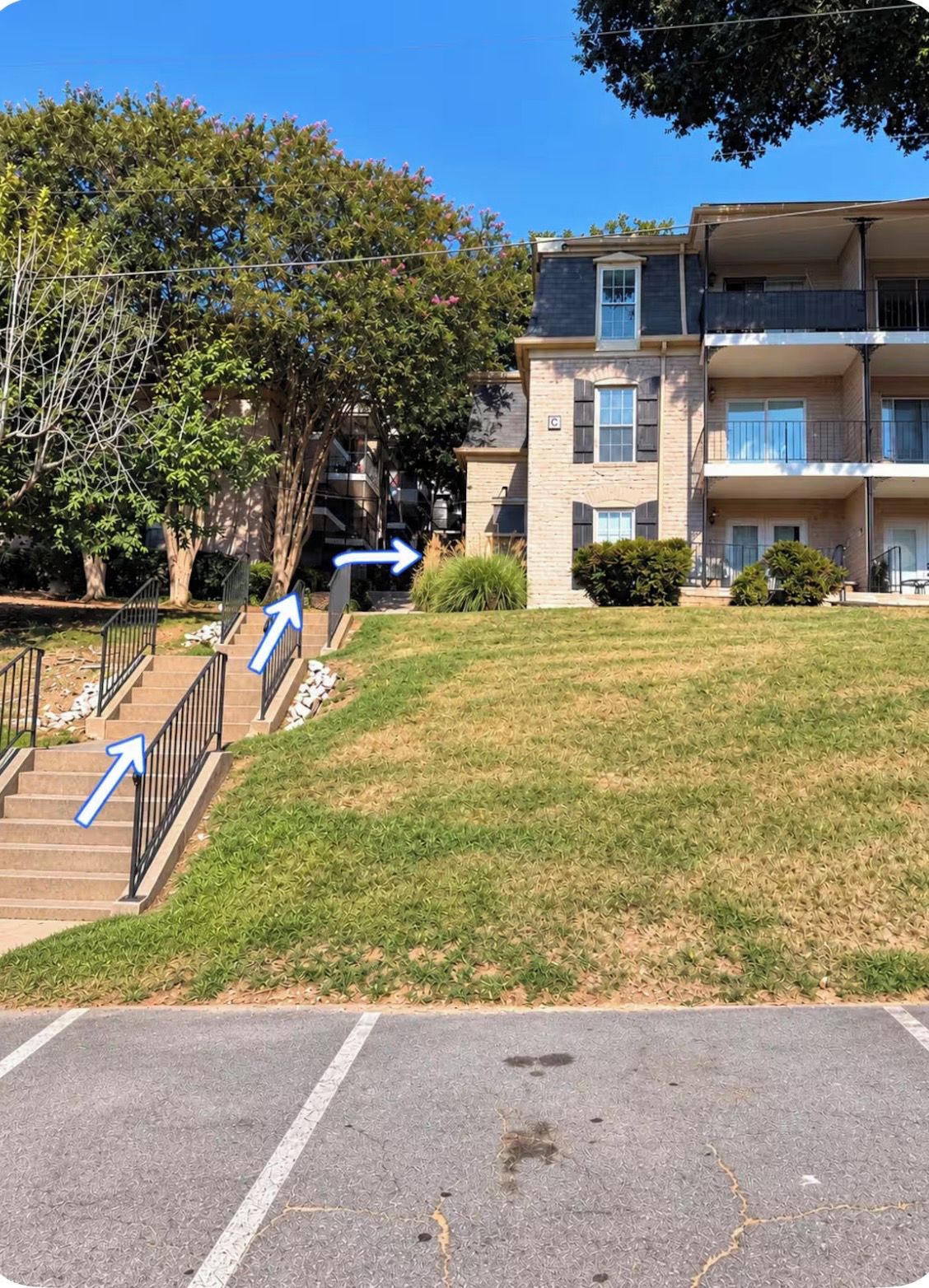Un edificio residenziale con un'area di parcheggio, una scala e un prato.