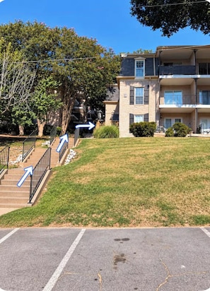 Un edificio residenziale con un'area di parcheggio, una scala e un prato.