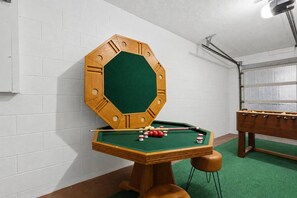 A pool table with a wooden octagonal frame and a green felt surface, accompanied by pool cues and balls. - Brandon Tropical Retreat |Private Pool & Hot Tub | Game Room | Near Tampa & Busch Gardens | Sleeps 7 (Brandon)