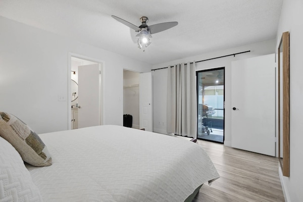 The primary king bed in this Brandon home's main suite offers ample comfort, complete with a ceiling fan and a private sliding door to the outdoor pat
