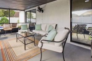 A covered outdoor seating area with a sofa, chairs, and a coffee table. - Brandon Tropical Retreat |Private Pool & Hot Tub | Game Room | Near Tampa & Busch Gardens | Sleeps 7 (Brandon)