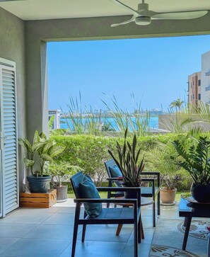 A balcony with a view of the sea, potted plants, and outdoor furniture. - The Snapdragon Courtyard Garden (Montego Bay)