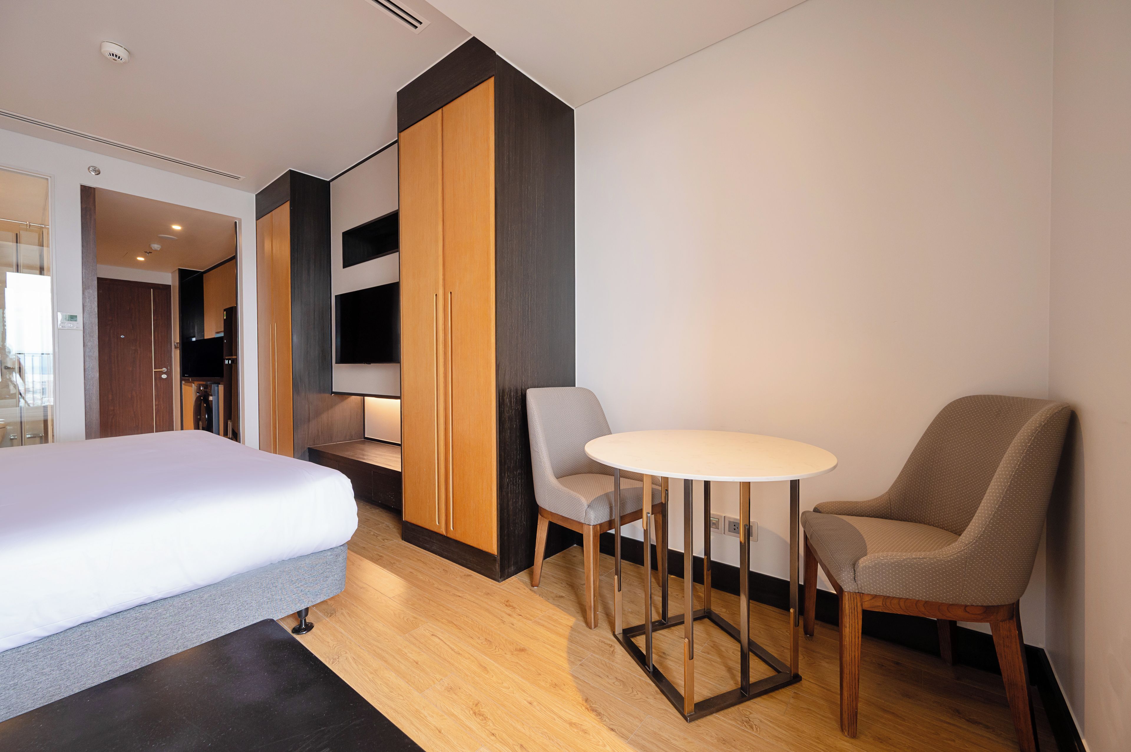 A hotel room with a bed, a seating area with a table and chairs, and a wardrobe.