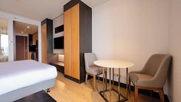 A hotel room with a bed, a seating area with a table and chairs, and a wardrobe.