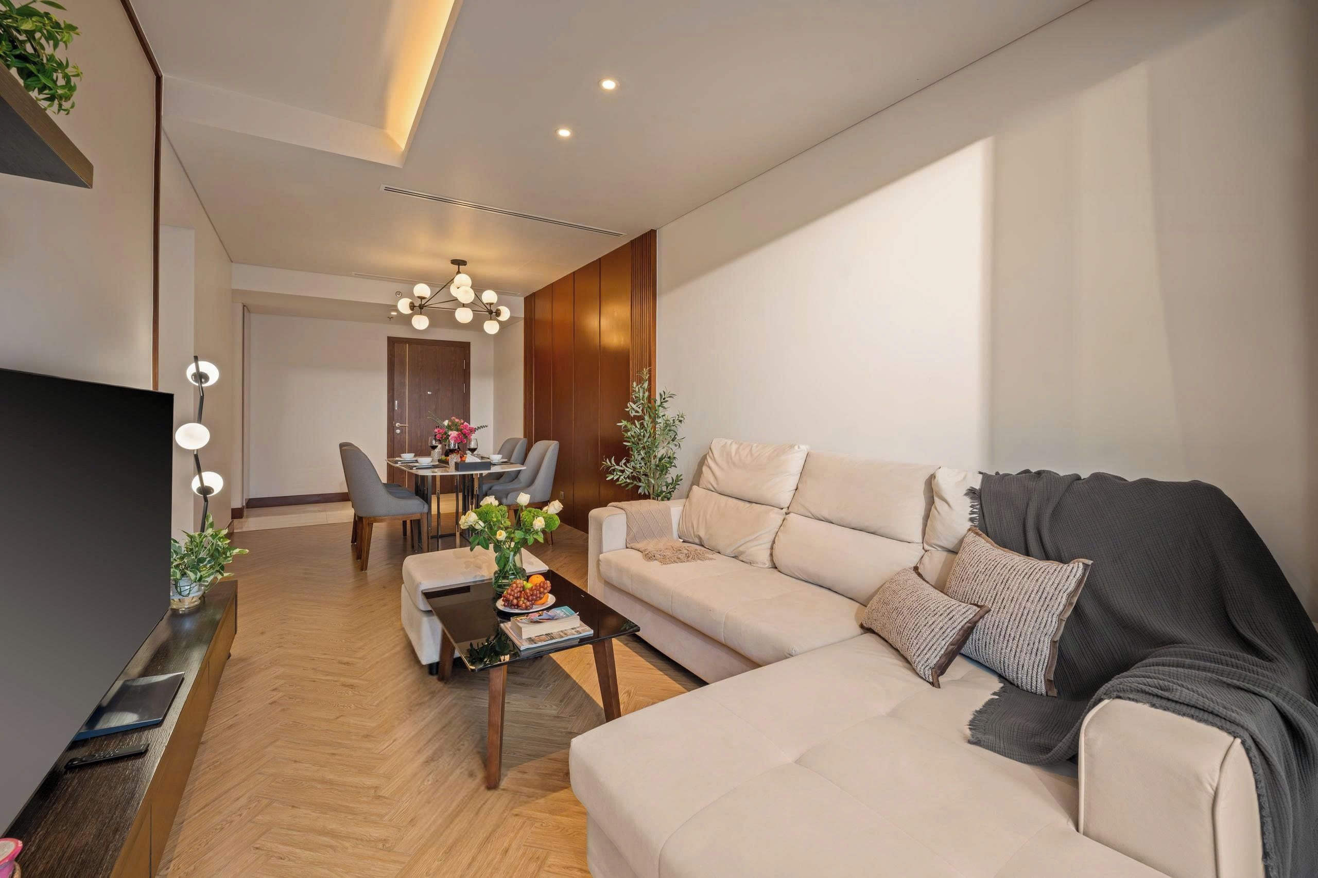 A modern living room with a sofa, coffee table, and a dining area with chairs and a table.