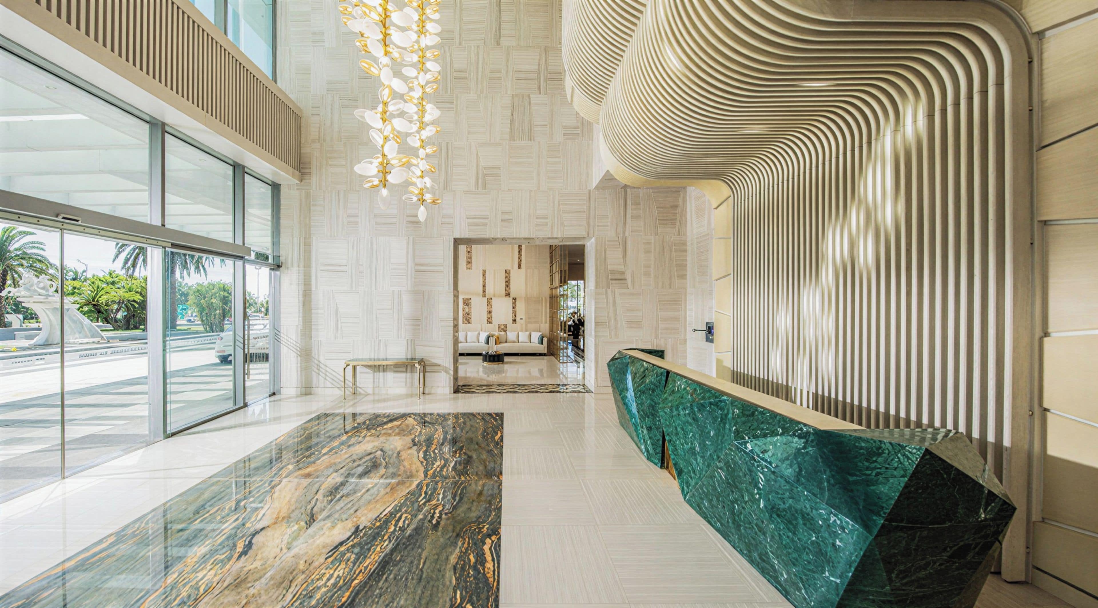 A modern lobby with a marble floor, a reception desk, and a patterned wall.