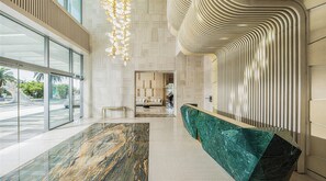 Um lobby moderno com piso de mármore, balcão de recepção e parede estampada.