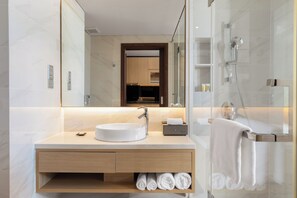 A modern bathroom with a large mirror, a sink, a shower, and neatly folded towels. - C Suite Danang (An Hai)