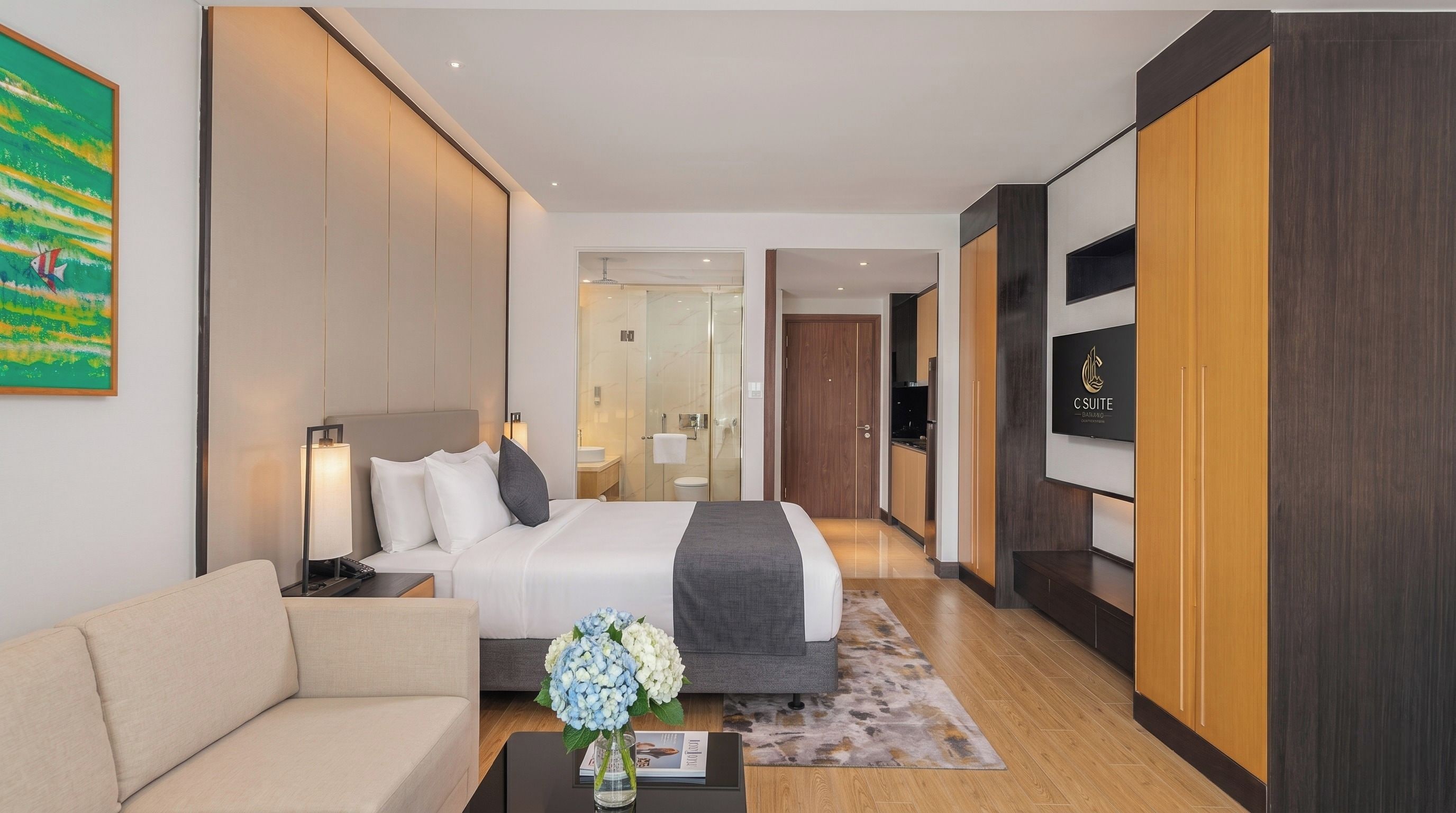 A modern hotel room with a bed, bedside table, lamp, and a view of the bathroom.