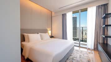A hotel room with a large bed, a nightstand, a lamp, a view of the city through the window, and a balcony with a railing.