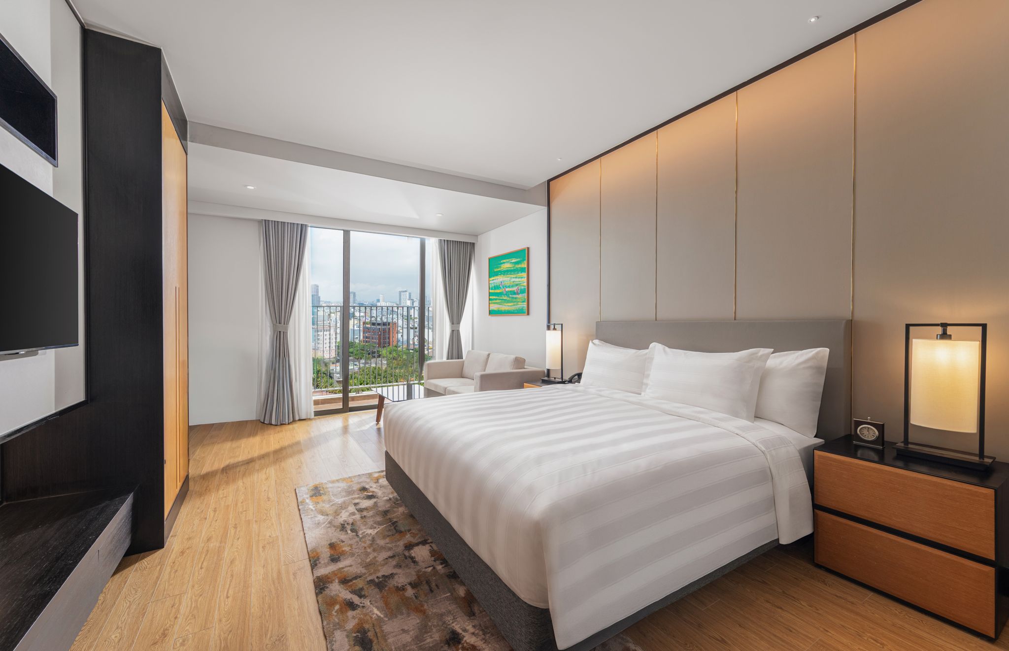 Een moderne hotelkamer met een groot bed, een bureau, een televisie en uitzicht op de stad.