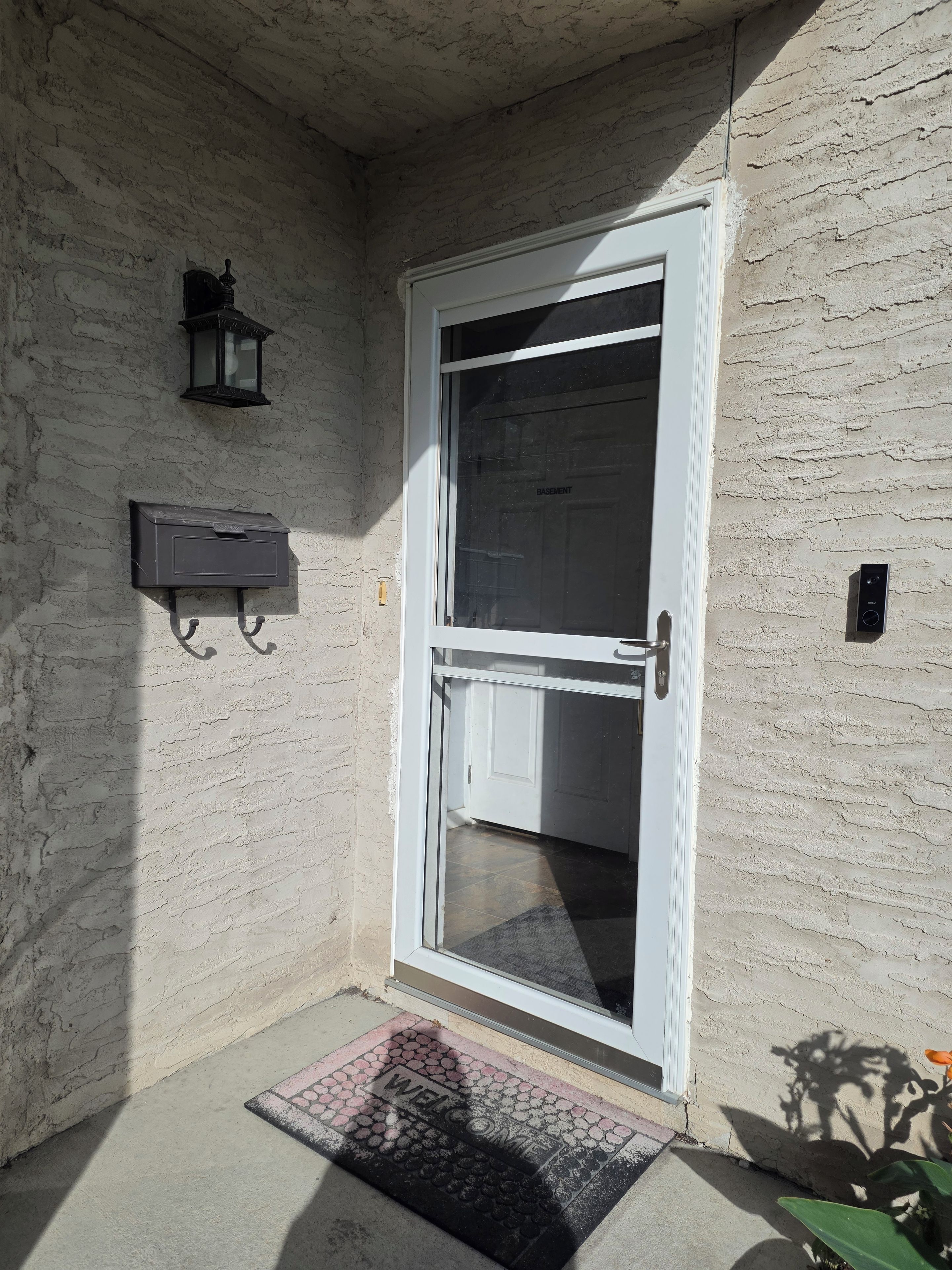 A door with a glass panel, a mailbox, and a welcome mat.