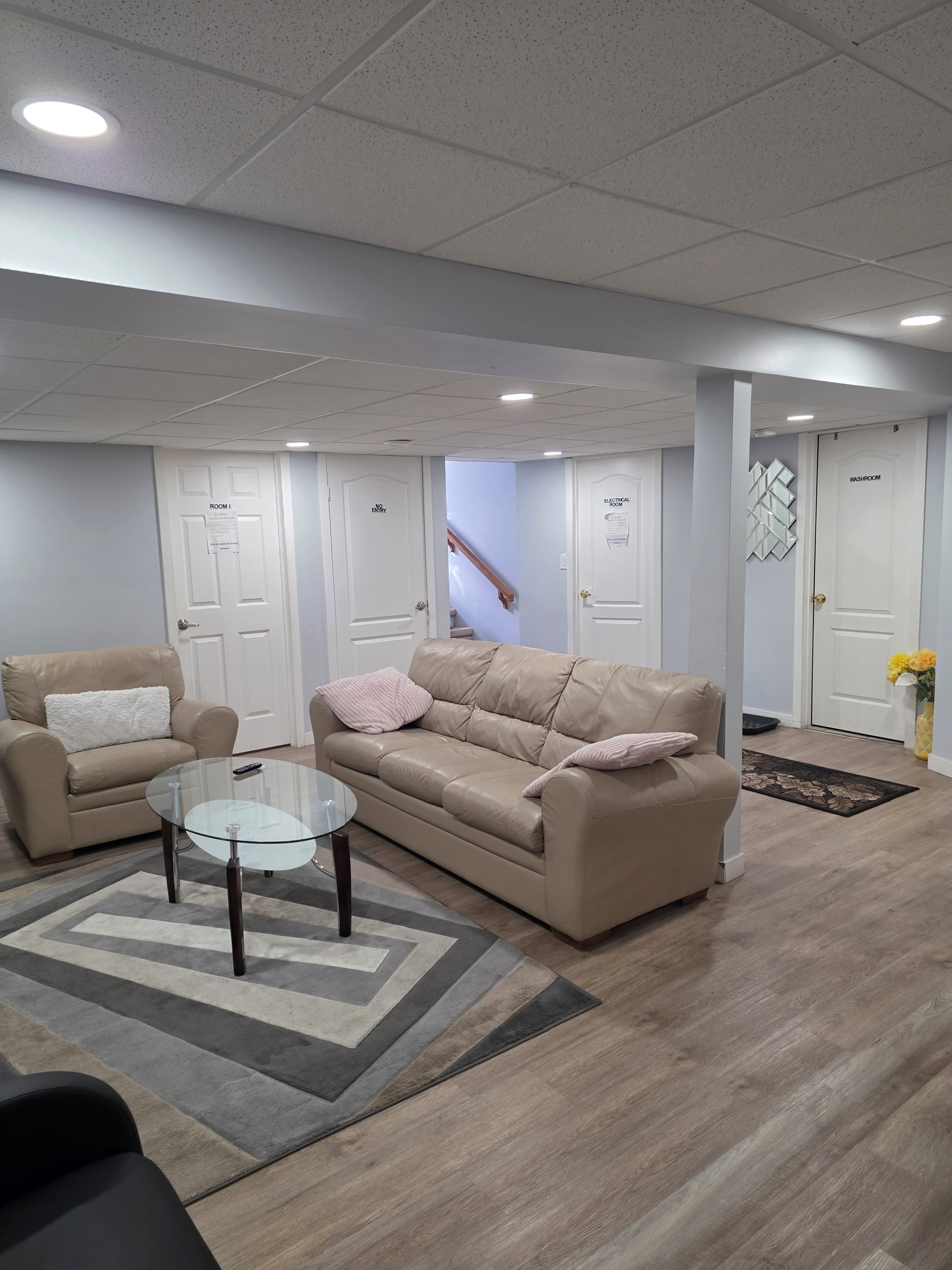 Una sala de estar moderna con un sofá color beige, una mesa de centro de cristal y una alfombra estampada.