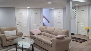 Una sala de estar moderna con un sofá color beige, una mesa de centro de cristal y una alfombra estampada.