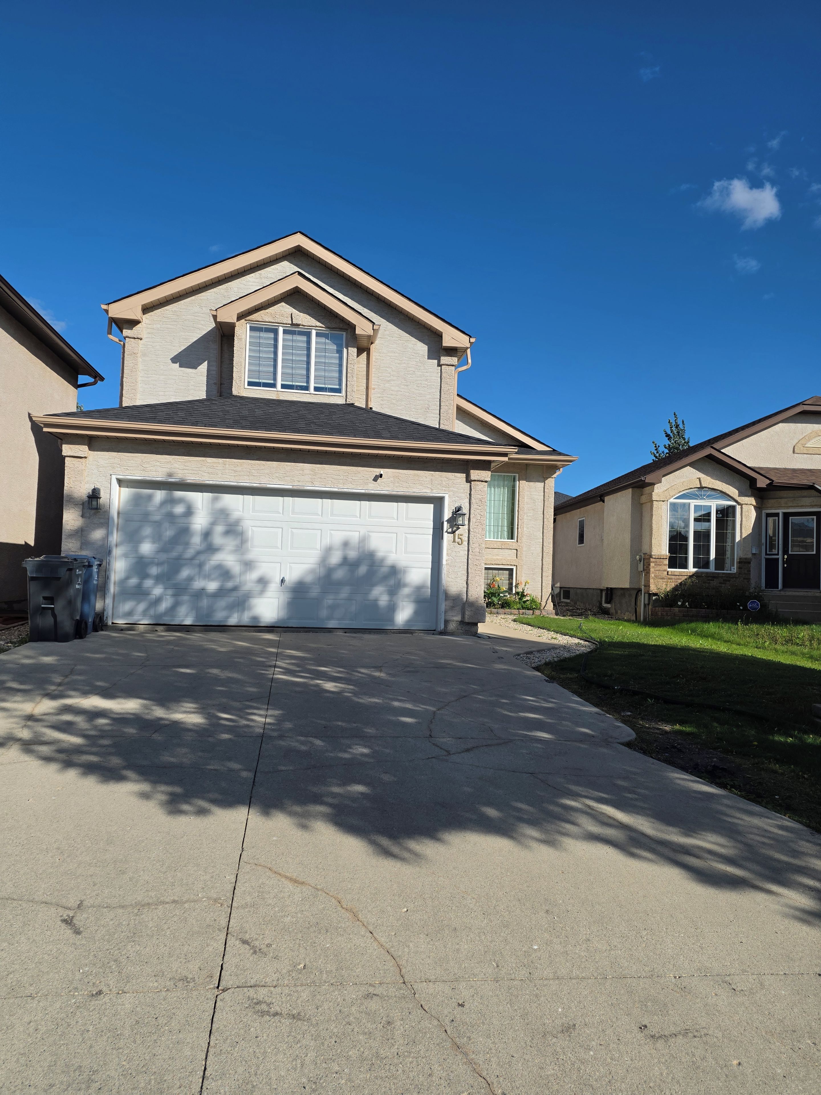 A residential house with a garage, a driveway, and a lawn.