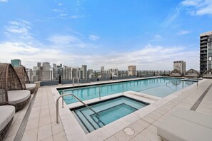 A rooftop swimming pool with a city view, surrounded by lounge chairs and a glass railing. - 501 First Corner Balcony by Palermo Home (Miami)