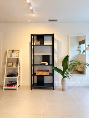 A modern living room with a black bookshelf, a white sideboard, and a large potted plant.