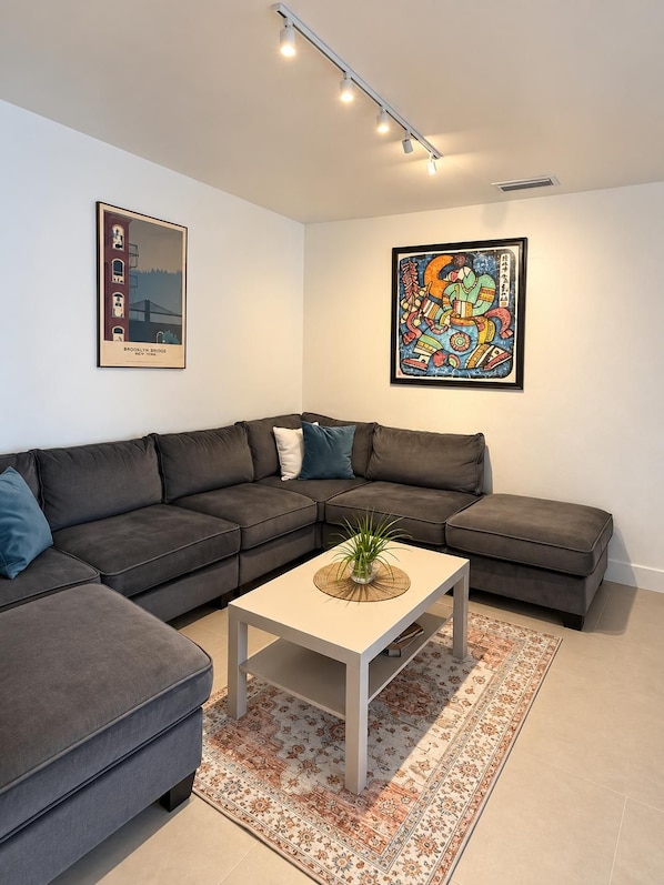 Un salon moderne avec un canapé d’angle, une table basse et deux œuvres d’art encadrées accrochées aux murs.