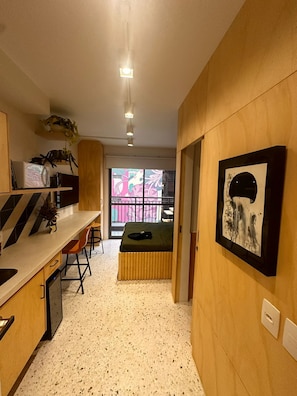 A compact living space with a kitchenette, a dining area, and a small bed. - Swimming pool on the rooftop studio, 3 minutes from República Metro station. (São Paulo)