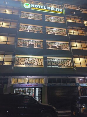 A hotel with a sign for 'Hotel Delite Accommodation & Restaurant' and a liquor store below. - Hotel Delite (Chuka)