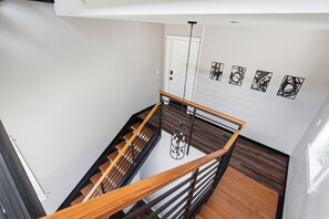 Ein modernes Interieur mit einer Holztreppe, einer Chandelüster und abstrakter Wandkunst.