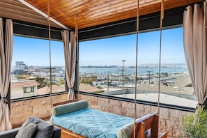 Ein Zimmer mit einem Bett, einer Schaukel und Blick auf Stadt und Wasser.