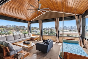 A spacious living area with a ceiling fan, large windows, and a city view. - Nutmeg Skyline 2BR in Downtown San Diego with patio, WiFi, parking. (San Diego)