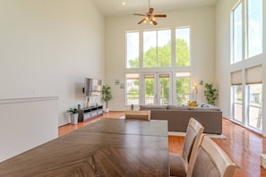 A spacious living room with a large dining table, a sofa set, a television, and a ceiling fan. - Sleeps 16 | 2 Adjacent EaDo Homes Near Stadium (Houston)