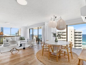 Uma sala de estar moderna com uma mesa redonda, cadeiras e vista para o oceano.